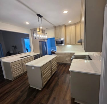 Modern kitchen featuring beige cabinets, quartz countertops, a central island, and dark wood flooring.