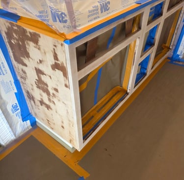 Sanded kitchen cabinets prepared for painting with 3M masking film and blue painter's tape.