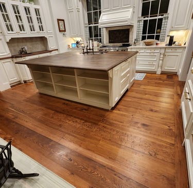 Spacious luxury kitchen featuring white cabinetry, wide-plank hardwood floors, and a large wood-top island.