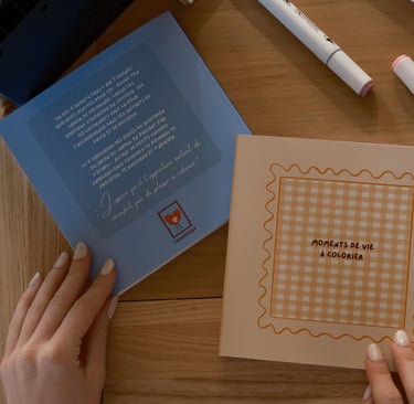 mains feuilletant un livre de coloriage posé sur une table avec feutres