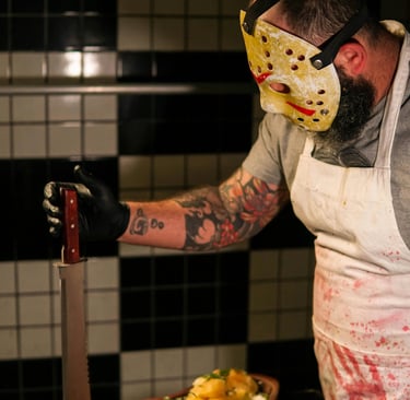 Blood-soaked man with knife in kitchen representing Grindhouse Gore Edition of Trivia from the Grave