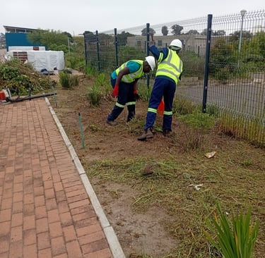 two men in safety vests working on a brick wall