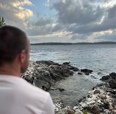 a man in white t shirt looks out to sea
