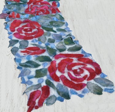 Handmade nuno felted wool scarf with red rose pattern and green leaves on a blue silk background.