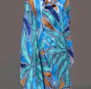 Handmade nuno felted scarf with blue, teal, and orange leaf patterns on a blue silk background.