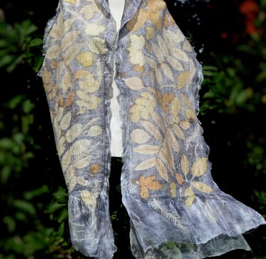 Handmade silk scarf with botanical print leaf patterns on a white mannequin outdoors.