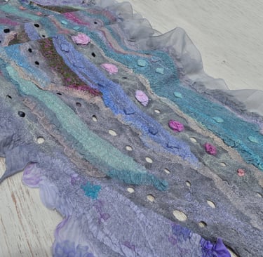 Handmade nuno felted scarf with blue and purple wool ripples, silk ruffles, and decorative holes.