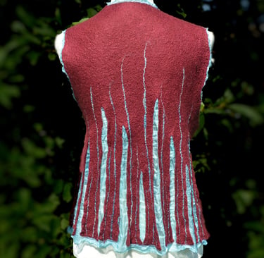 Handmade burgundy nuno felted wool vest with light green silk accents on a mannequin.