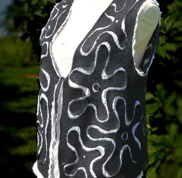 Handmade black nuno felted wool vest with white floral swirl patterns on a mannequin.