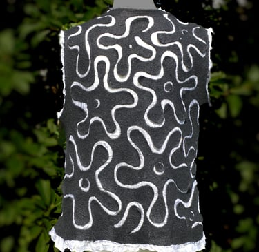 Handmade black nuno felted wool vest with white abstract floral swirl patterns and ruffled hem.