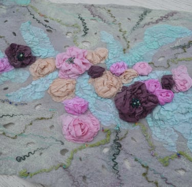 Handmade nuno felted wool scarf featuring intricate 3D silk fabric flowers in pink and purple tones.