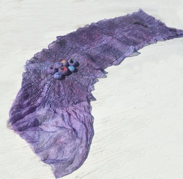 Handmade purple nuno felted silk scarf with decorative wool 3D elements on a white surface.