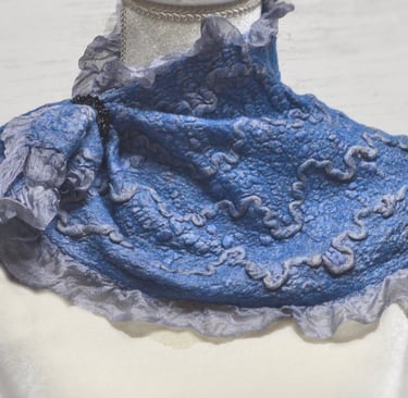 Handmade blue nuno felted wool neck warmer with ruffled edges and textured patterns on a mannequin.