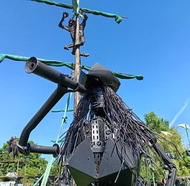Creative pirate ship sculpture made of recycled metal scrap art under a clear blue sky.