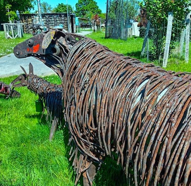 Rustic metal sheep sculpture made of recycled rebar and scrap metal in a sunny garden.