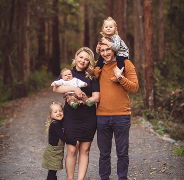 a family of three standing in a wooded area