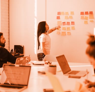 a woman standing in front of a white board with sticky notes on it