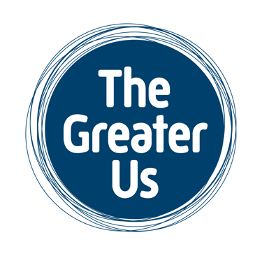 A circular blue logo with the name "The Greater Us" written inside