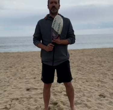 a man holding a tennis racket on a beach