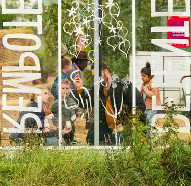 Un adulte et des enfants dessiner sur une verrière avec un feutre blanc