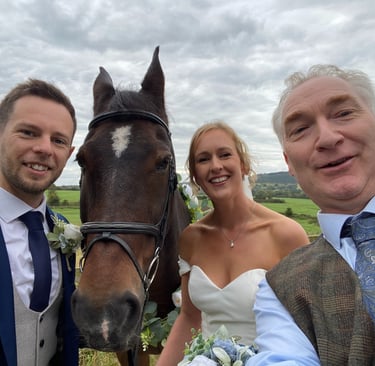a bride and groom posing for a photo with a horse and celebrant
