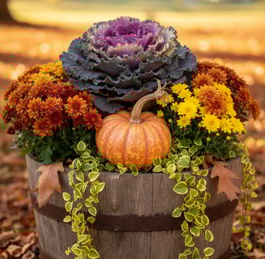 Rustic wooden barrel planter featuring fall mums, an ornamental cabbage, and a small pumpkin.