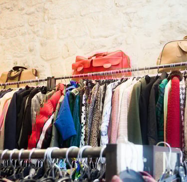 A full rack of long sleeve clothes with purses on top