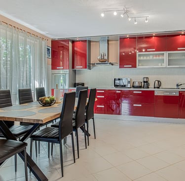 Spacious modern red kitchen with a large dining table for 8 at Villa Nika in Škrip, island of Brač