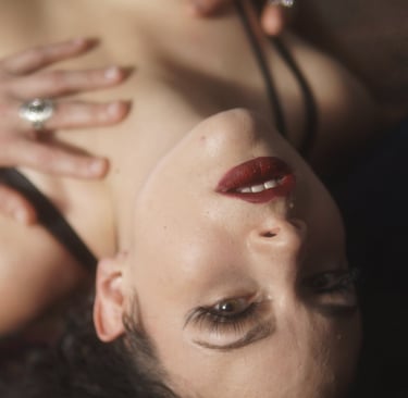 a woman in a black lingersuite laying down with red lipstick