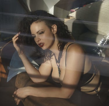 a woman in black lingerie suit on a sofa seen through a window