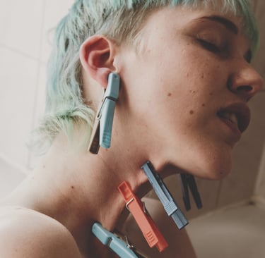 a woman with blue hair and clothespins on her skin