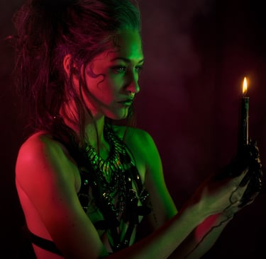 a woman wearing a harness, green and red light on her skin, holding a candle