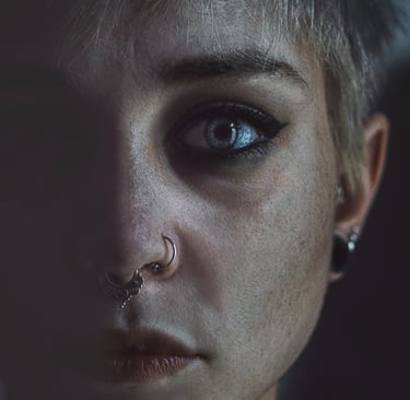 a woman with piercings blue eyes lipstick, half face in shadow half in light