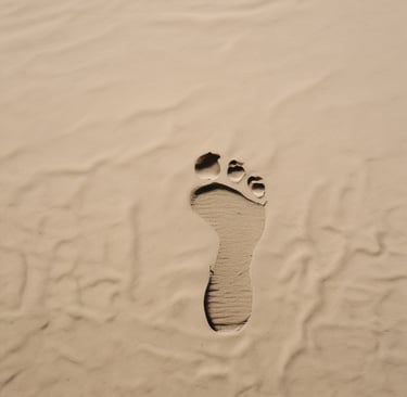 a person laying on a beach with their feet in the sand