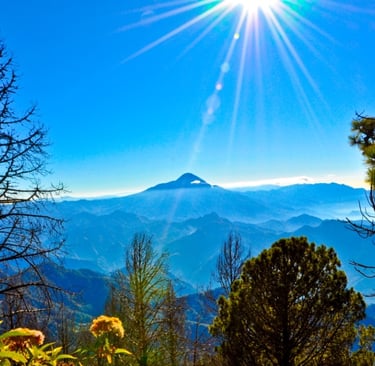 Tacaná Volcano from a distance with vivid blue skies and sun shining above with foreground trees