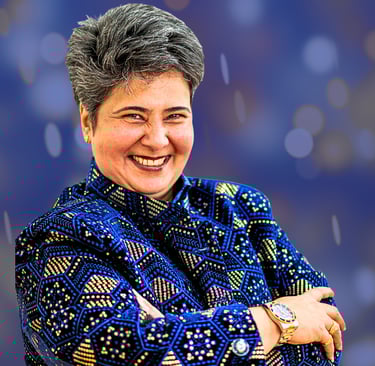Indian woman with short hair smiling at camera. She is wearing a navy blue jacket with gold spots