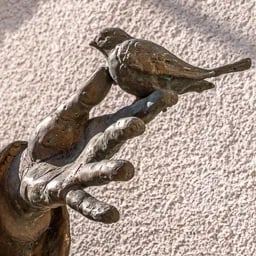 Close up on the hand of Saint Francis with a bird.