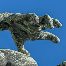 Close up on the hand of the archer statue.