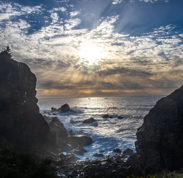 Sunlight breaks through clouds over rocky cliffs and turbulent sea, symbolizing balance 