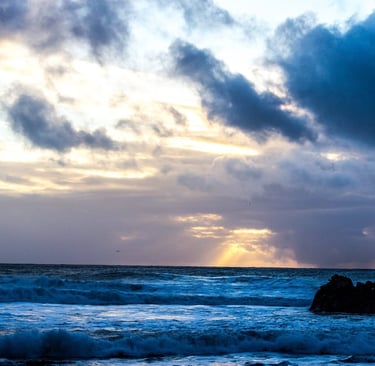 A sunrise breaking through storm clouds over shifting ocean waves