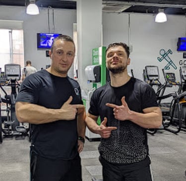 two men standing in a gym with their hands up