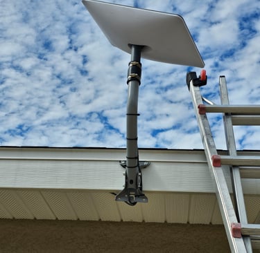 Starlink satellite dish mounted on a home rooftop with a clear blue sky background.