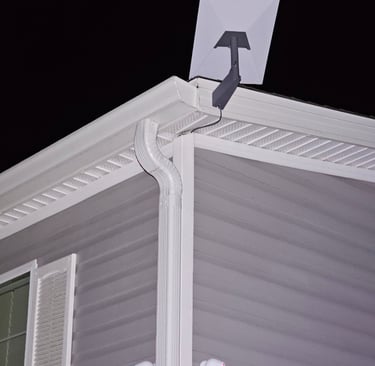 A rectangular Starlink satellite internet dish mounted on the roof of a house at night.