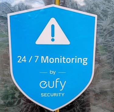 Eufy Security window decal showing 24/7 monitoring services on a blue shield logo.