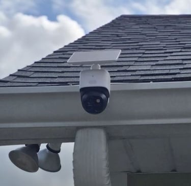 White solar-powered wireless outdoor security camera mounted on a residential roof gutter system.