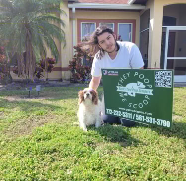 Alex smiling, one of the scoopers, posing with his dog and poop scoopers yard sign at customers home