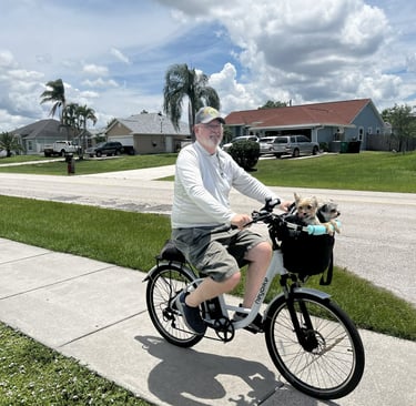 Robert riding a bicycle with a dog in a basket