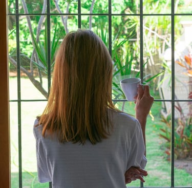 a woman holding a cup of coffee in front of a window