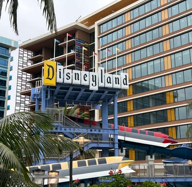 A retro-style "Disneyland" sign rests above the themed pool slide in the Disneyland Hotel courtyard,