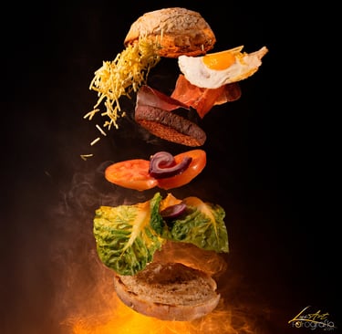 Fotografía gastronómica de hamburguesa con ingredientes flotando como pan, huevo, bacon, verduras y 